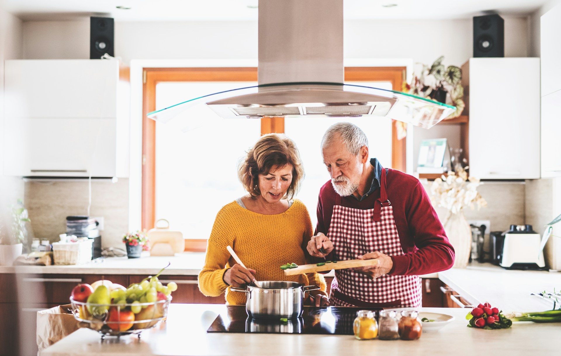a senior couple cooking together add green beans to a pot on the stove